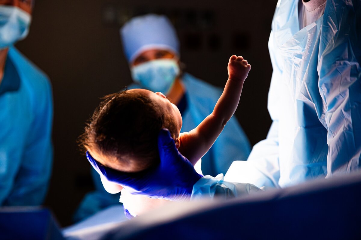 Image shows healthcare professionals holding a newborn baby