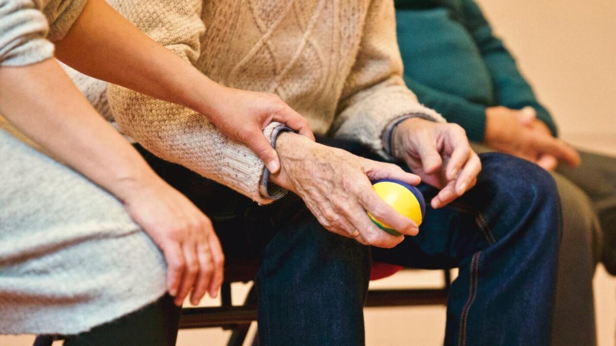 Image shows the hands of an elderly person holding a ball